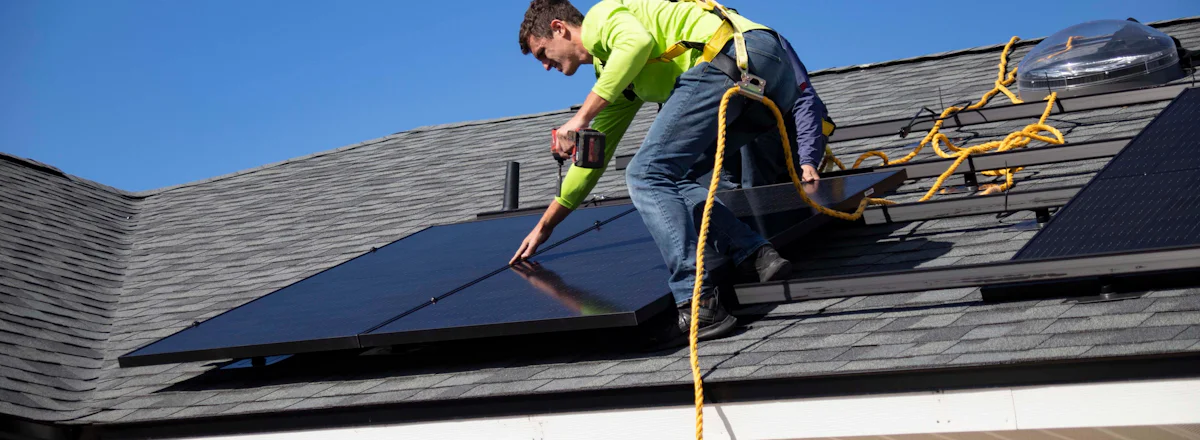Instalador fijando paneles solares en el tejado de una vivienda